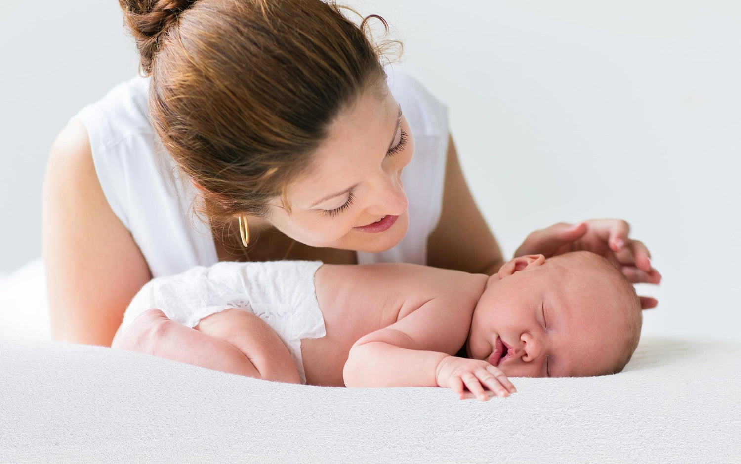 Parent watching over a baby on a protected crib mattress